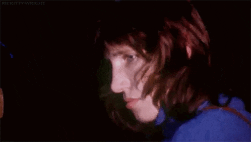 a close up of a person 's face in the dark with a blue shirt on .