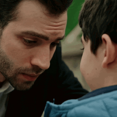 a man and a boy are looking at each other and the boy is wearing a blue jacket