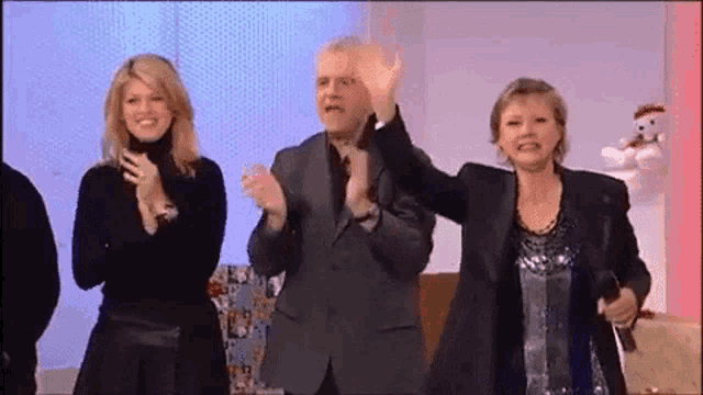 a group of people are standing next to each other on a stage and applauding .