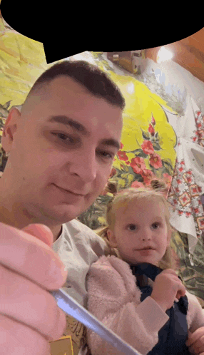 a man is holding a little girl in his arms while holding a toothbrush