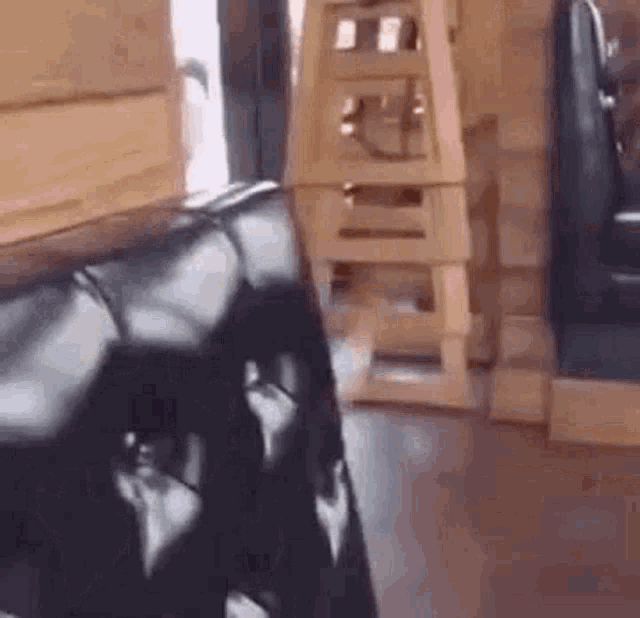 a black leather couch is sitting in a restaurant next to a wooden ladder .