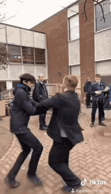 a man in a suit is standing next to another man in a suit in front of a building with a tiktok watermark