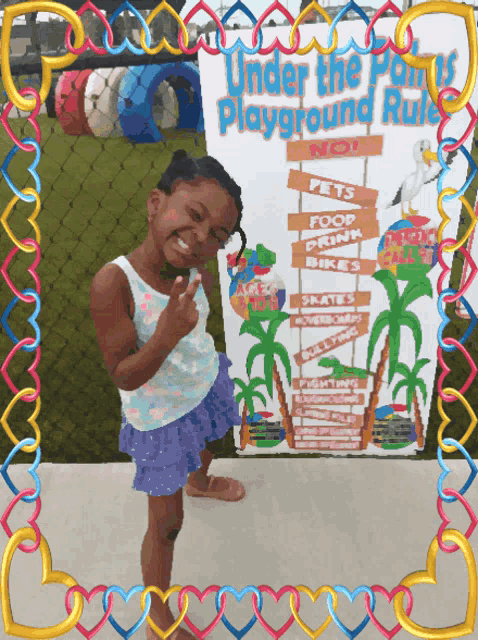 a little girl is standing in front of a sign that says under the playground rule