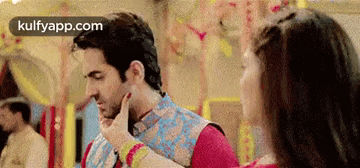 a woman is touching a man 's face while a man looks on .