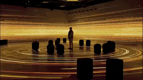 a man is standing in a room with a lot of lights behind him