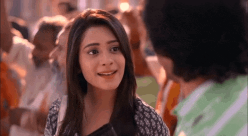 a woman is smiling while talking to a man in a crowd of people .