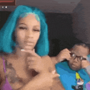 a woman with blue hair is sitting next to a little boy with glasses .