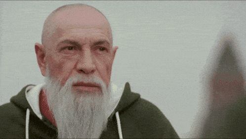 a bald man with a long white beard wearing a green hoodie