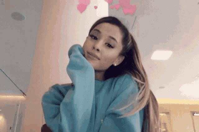ariana grande is wearing a blue sweater and a crown of hearts .