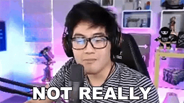 a man wearing headphones and glasses is sitting in front of a microphone and saying not really .