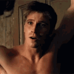 a shirtless man is standing in front of a mirror with his arm up .