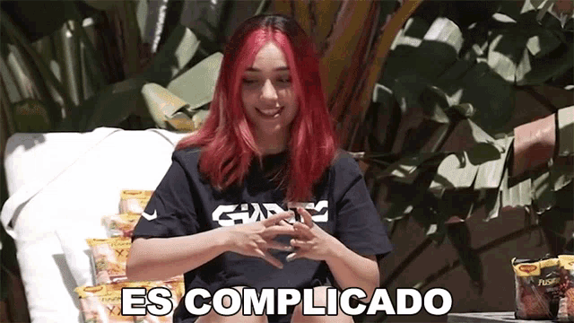 a girl with red hair is sitting on a couch and says es complicado in spanish