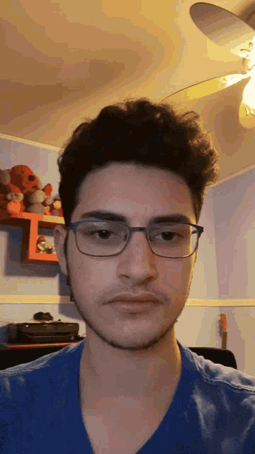 a young man with glasses and a blue shirt looks at the camera