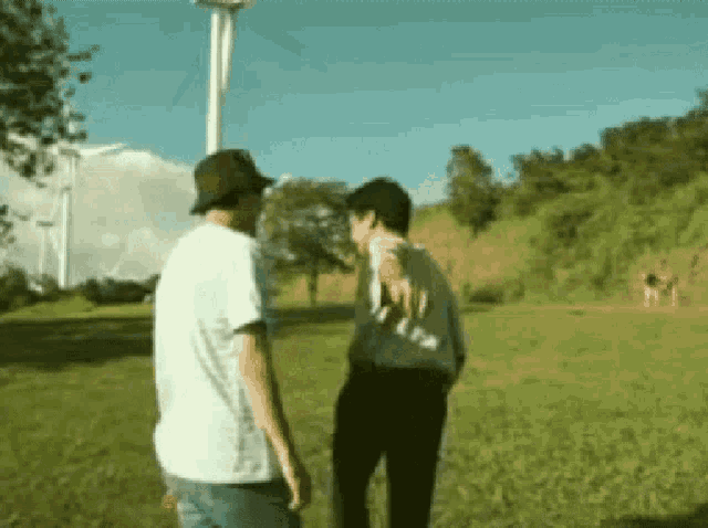 two men are standing in a grassy field talking