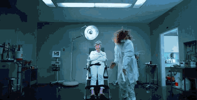 a woman in a straitjacket sits in an operating room with a doctor