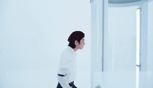 a young man wearing a beret and a white shirt is looking out a window .