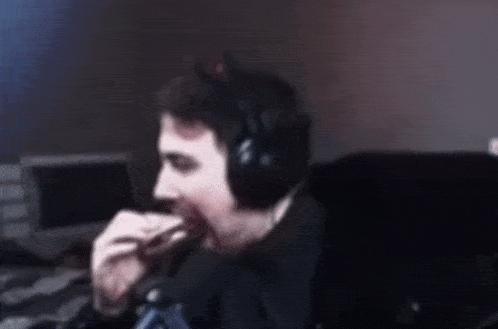 a man wearing headphones and a cat ear is smoking a cigarette while sitting in a chair .