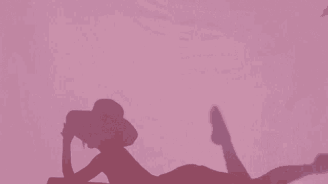 a shadow of a woman wearing a hat laying on her stomach