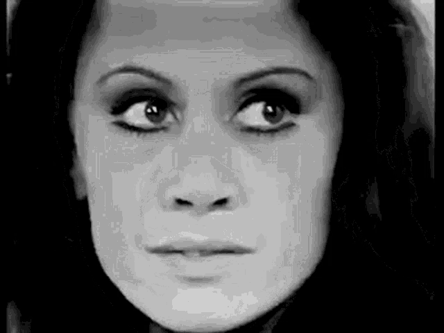 a black and white photo of a woman 's face looking at the camera .