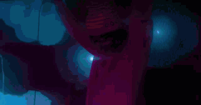 a person wearing glasses and a pink hat is standing in front of a blue light