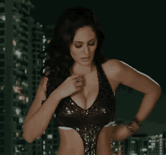 a woman in a white bra is standing in front of a city skyline at night