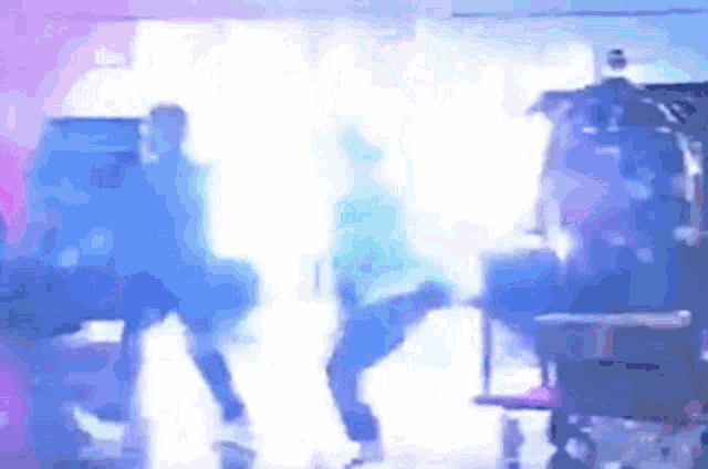 a group of people are standing in a room with a purple light coming out of the ceiling .