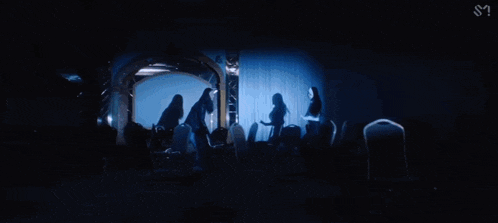 a woman is standing in a dark room in front of a light .