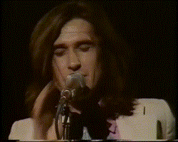 a man is singing into a microphone with his eyes closed