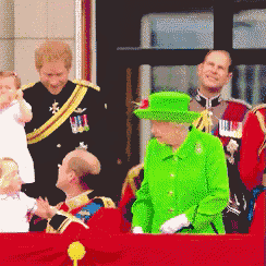 queen elizabeth wearing a green hat stands in front of a group of people