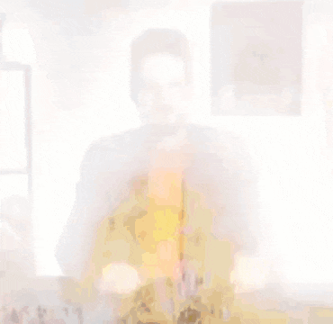 a blurry picture of a man in a red shirt and a brown jacket .