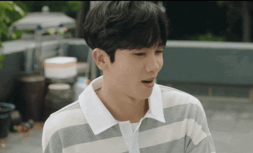 a young man wearing a striped shirt looks at the camera