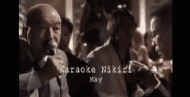 a man in a suit is singing into a microphone in a crowd .