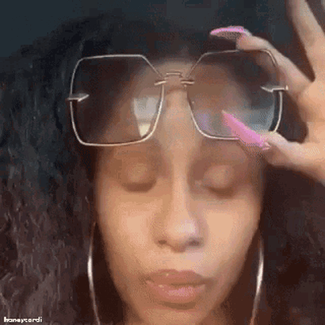 a close up of a woman wearing sunglasses and earrings with her eyes closed .