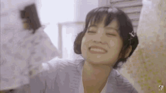 a woman is smiling while holding a piece of paper in her hands .