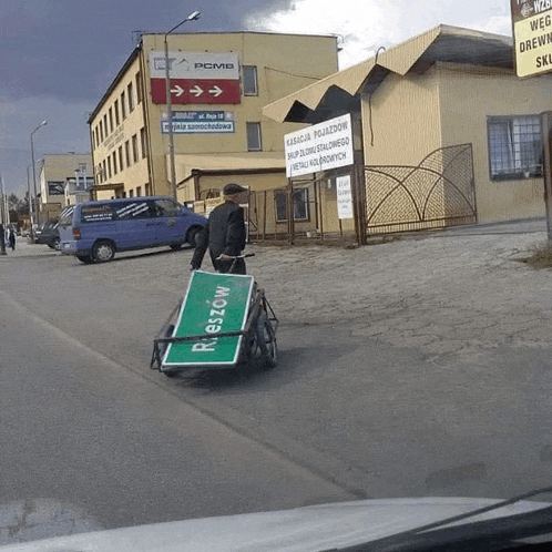 a man pushing a cart with a green sign that says reszow on it