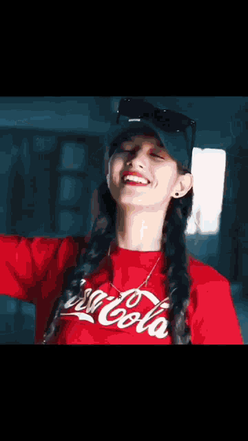 a woman wearing a red coca cola t-shirt and a hat is smiling .