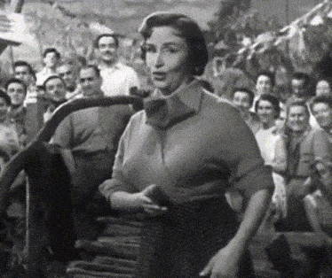 a woman is standing in front of a crowd of people and talking