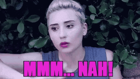 a woman in a blue tank top is standing in front of a bush with the words `` mmmm ... nah ! ''