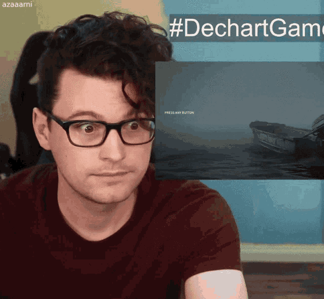 a man wearing glasses and a red shirt looks at a screen that says press any button