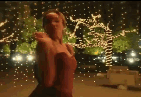 a man in a suit and a woman in a red dress are dancing in a park .