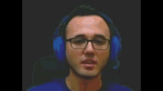 a man wearing glasses and blue headphones looks at the camera .