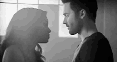 a black and white photo of a man and woman looking at each other .