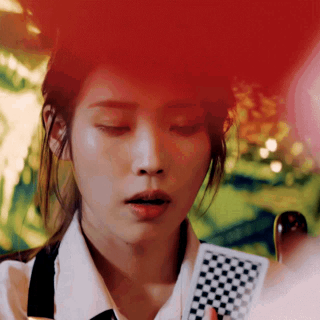a woman with her eyes closed holds a checkered card