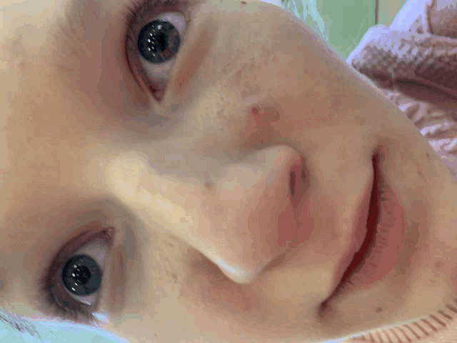 a close up of a woman 's face with blue eyes and freckles