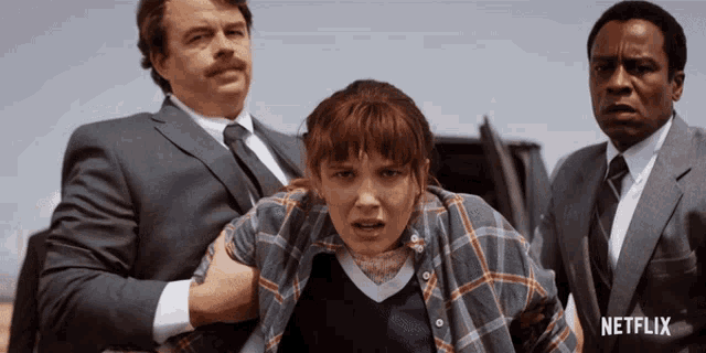 a man in a suit and tie is holding a girl in a plaid shirt with a netflix logo in the background
