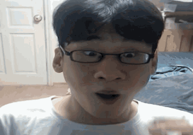 a man wearing glasses and a white shirt is making a funny face