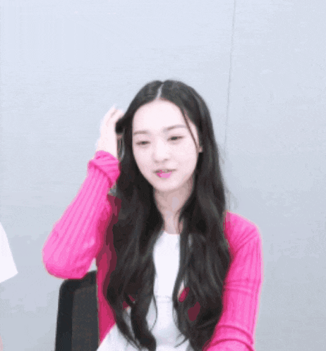 a woman with long black hair is wearing a pink sweater and a white shirt
