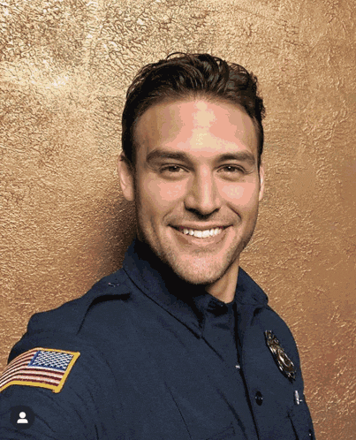 a man in a police uniform has an american flag patch on his shoulder