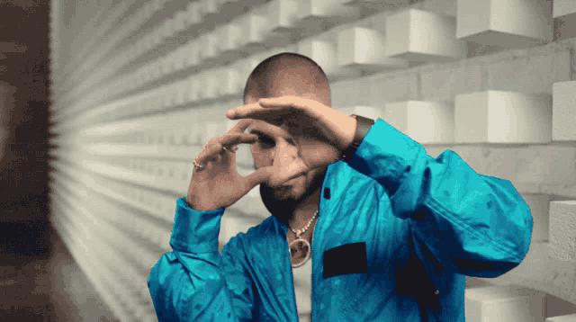 a man in a blue jacket is making a funny face with his hands