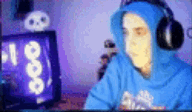 a person wearing headphones and a blue hoodie is playing a video game on a computer .